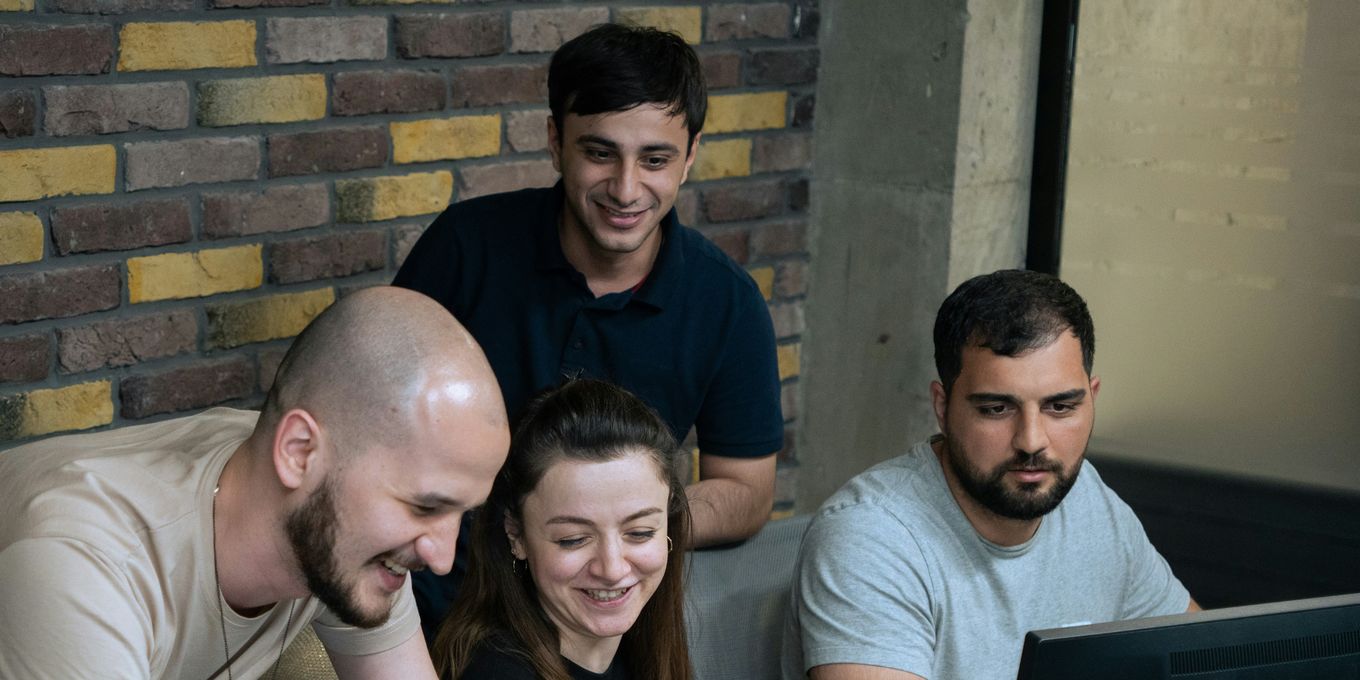 A media team of four smiling as they review results together on a monitor