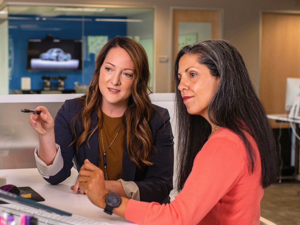 Two marketing leaders reviewing work together on a computer screen