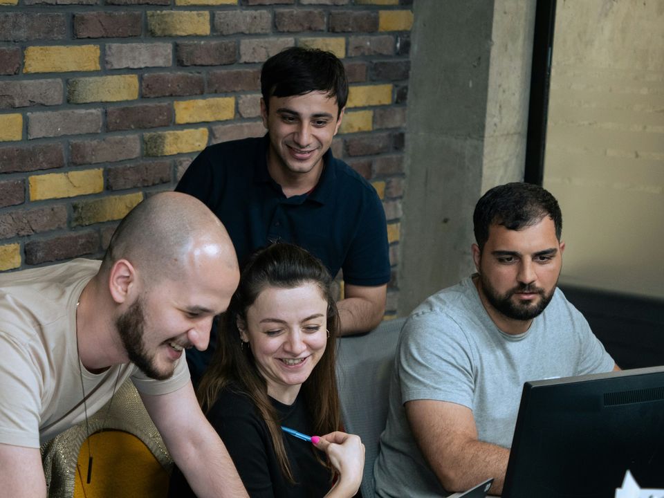 A media team of four smiling as they review results together on a monitor