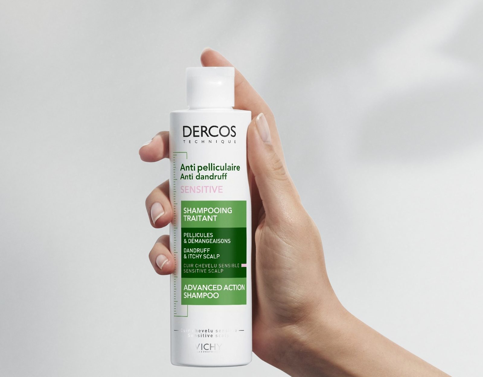 A hand holding a bottle of Vichy Dercos anti-dandruff shampoo