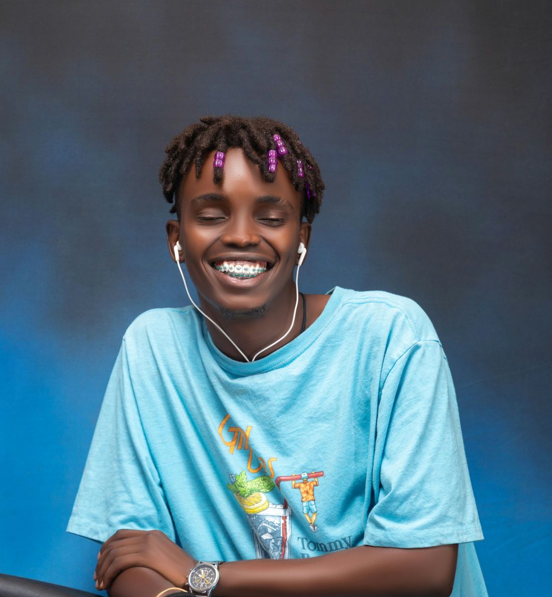 Smiling young man with earphones against a blue background