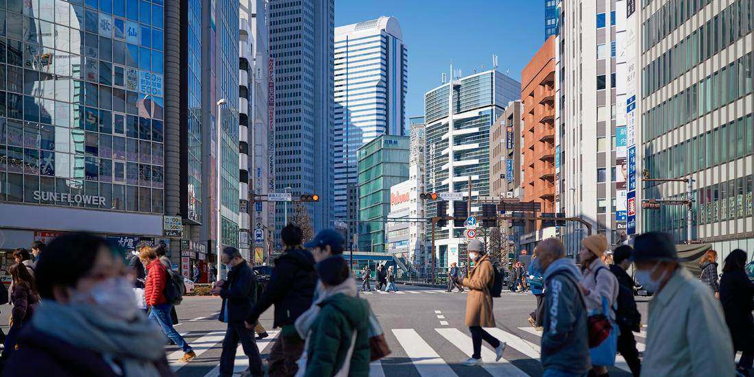 Pedestrians crossing a city street lined with office towers