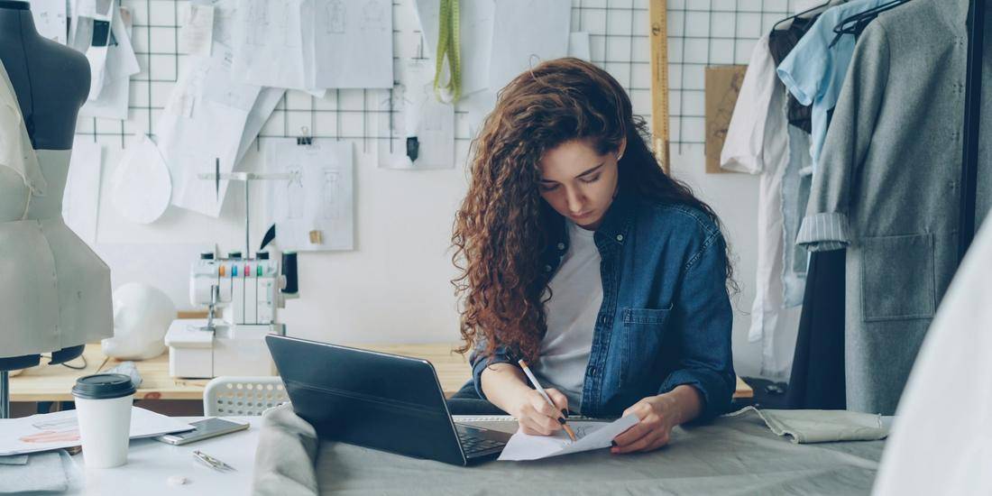 Designer taking notes at a laptop in a fashion studio