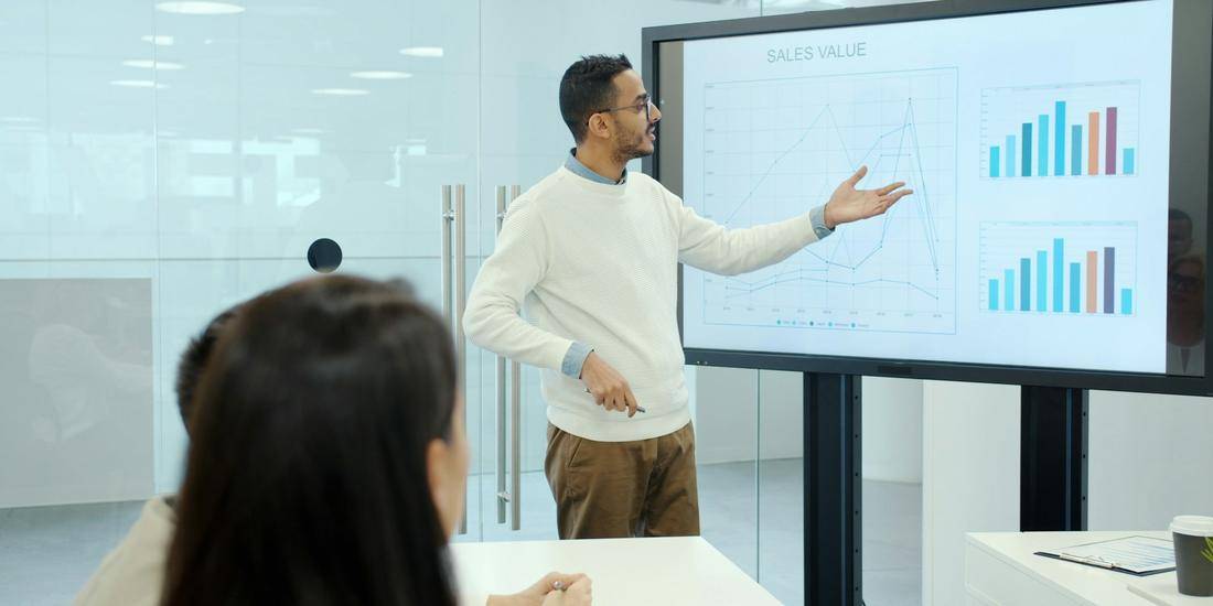 Presenter walking colleagues through charts on a screen