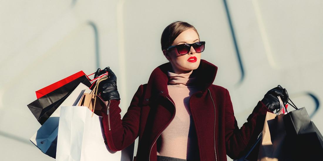 Woman in a red coat carrying several shopping bags