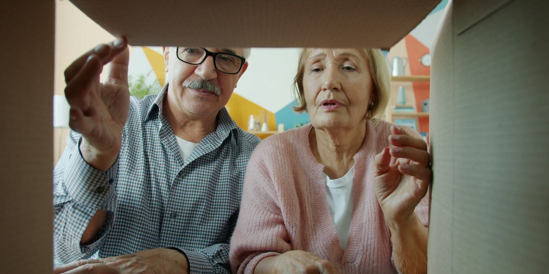 Couple looking into an open cardboard delivery box, seen from inside the box